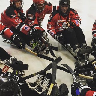 Cardiff Huskies Para ice hockey players in a circle with their sticks together doing a huddle