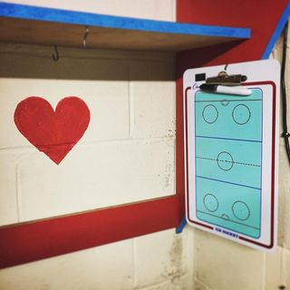 Hanging ice hockey coaching drill board next to  red heart painted on the wall
